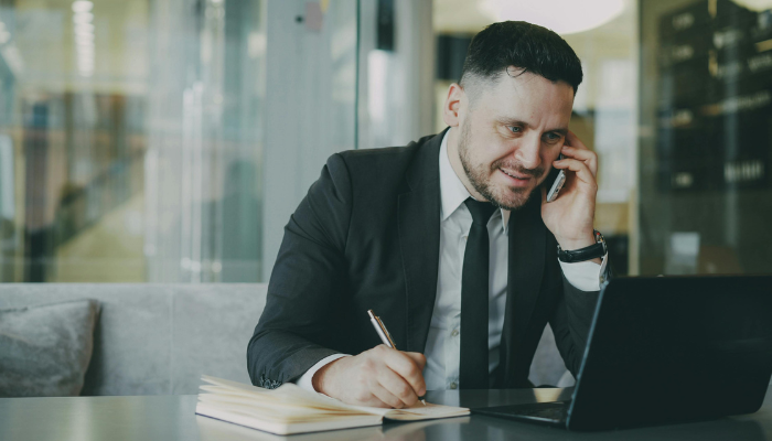 Business owner on a phone call while taking notes and following up on overdue invoices
