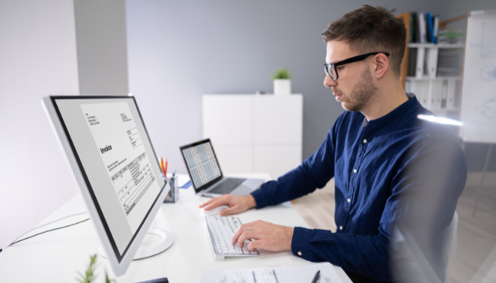 Business professional reviewing an invoice on a desktop screen to process billing more efficiently