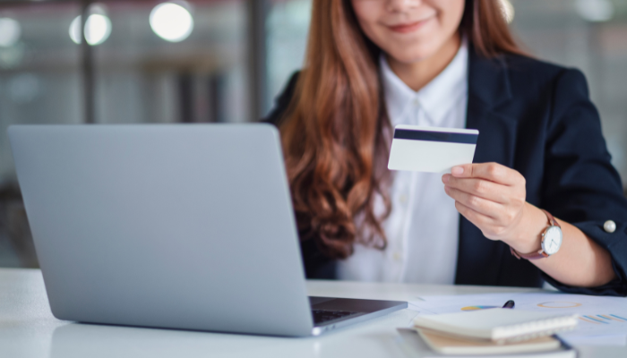 Professional holding a payment card at a laptop to complete a business payment online