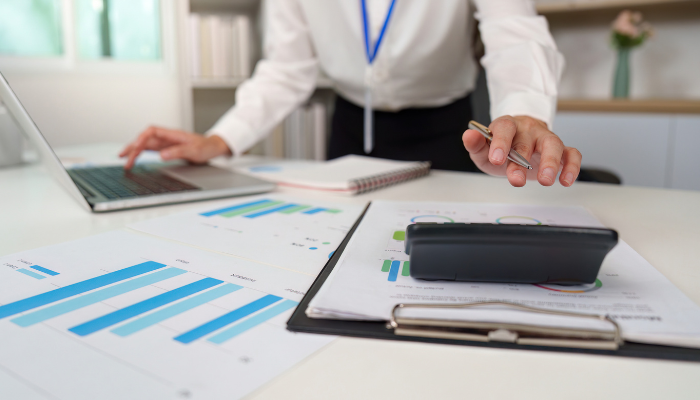 Business professional reviewing financial reports and a calculator while tracking receivables