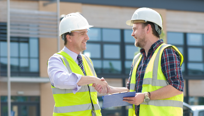 Contractor and project manager shaking hands on a job site