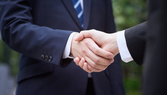 Two business professionals shaking hands, symbolizing strong partnerships between banks and factoring companies.