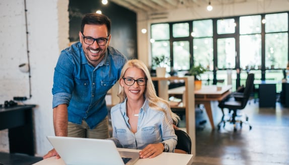 Small business owners reviewing their finances on a laptop, demonstrating the positive impact of stable cash flow on daily operations.