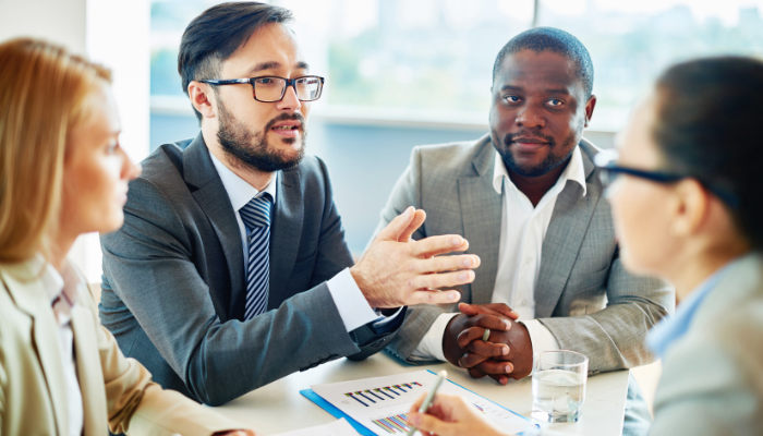 Bankers and financial professionals in a meeting discussing how factoring partnerships help protect long-term banking relationships.