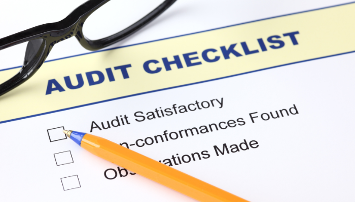 Close-up of an audit checklist form with a pen and glasses, representing compliance and business credit accuracy.