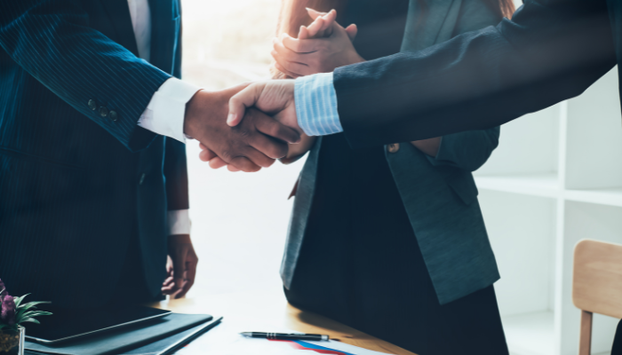 Two business professionals shaking hands in an office setting, indicating trust and partnership built through credit.