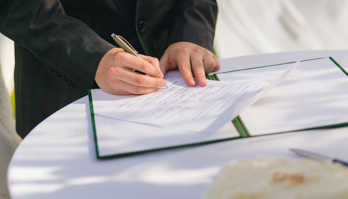 Professional signing official documents on a table, symbolizing business registration and identity verification.