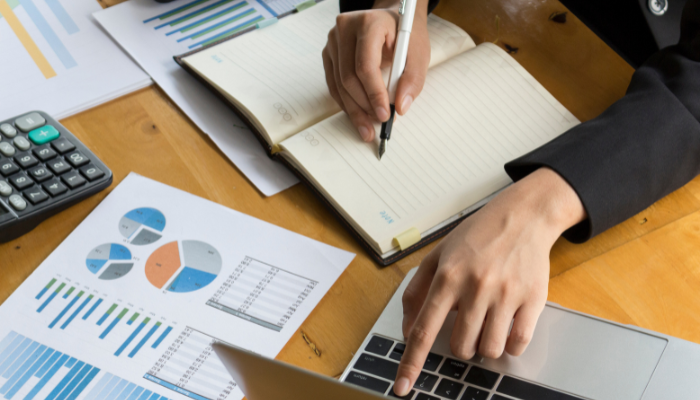 Person analyzing graphs and data while typing on a laptop, representing credit strategy and financial analysis.