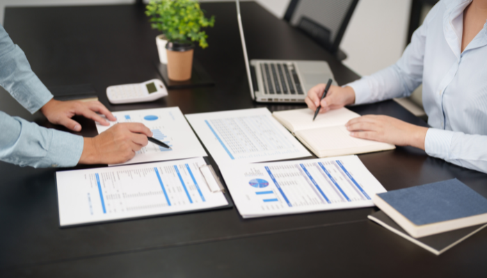 Businessperson reviewing and explaining a financial document with a pen, with a pen on the desk.