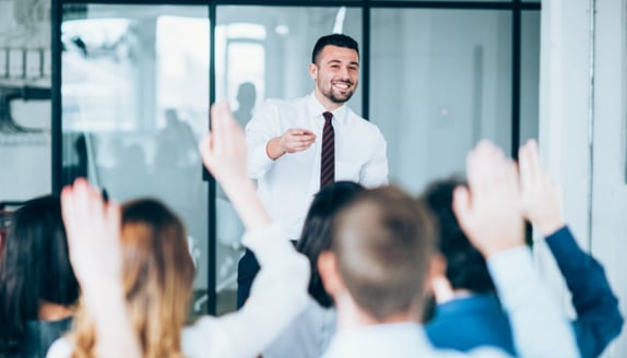 Instructor engaging a class as participants raise hands for business training
