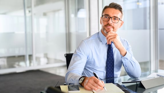 Business leader reflecting and taking notes while planning next year’s goals and budget