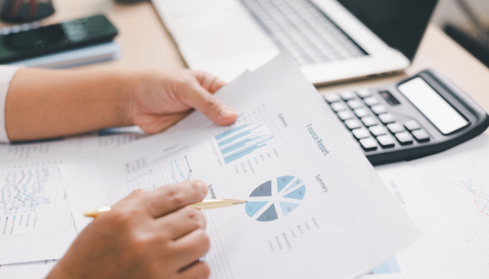 Business owner reviewing financial reports and charts to plan expenses and improve cash flow management.