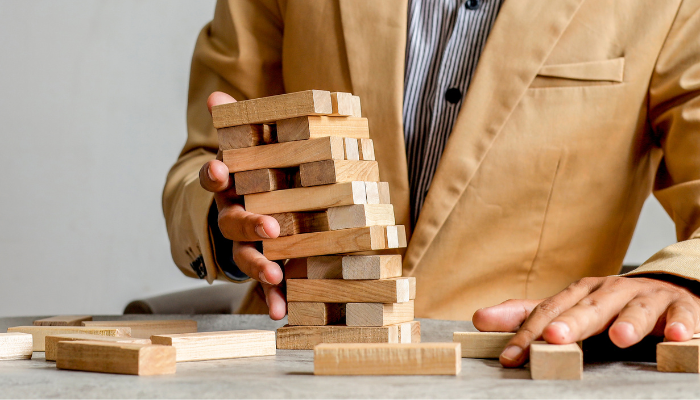 Business owner stabilizing a stack of wooden blocks representing financial stability and managing cash flow risk.
