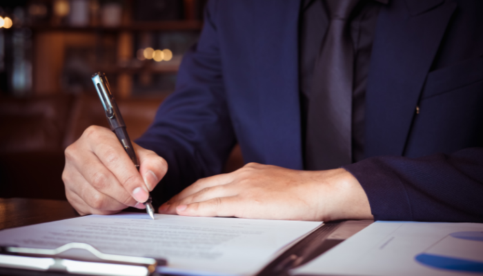 Entrepreneur signing a loan agreement with financial documents on the table.
