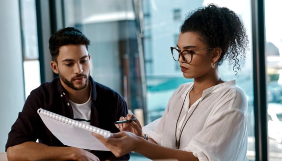 Business owner reviewing invoices and payment timing with financial advisor to improve cash flow planning
