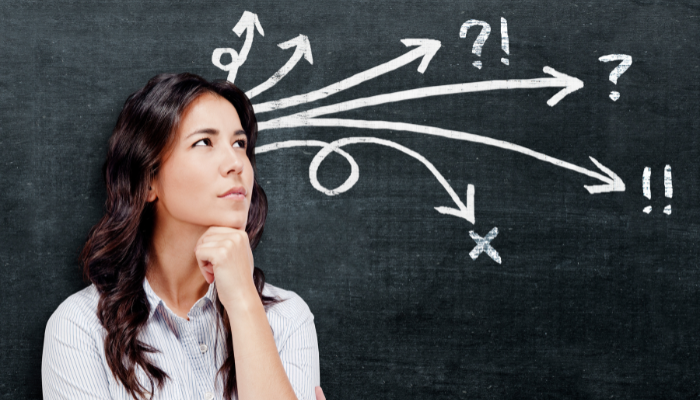 Woman looking at chalkboard with arrows and question marks, representing complex financing decisions.