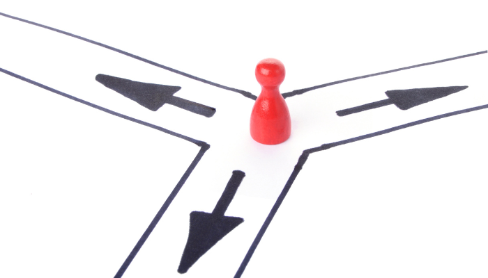 Red game piece placed at a three-way crossroads drawn in black arrows, symbolizing choice and direction.