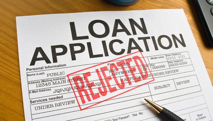 Close-up of a rejected loan application form with red stamp, illustrating difficulties with traditional lending.