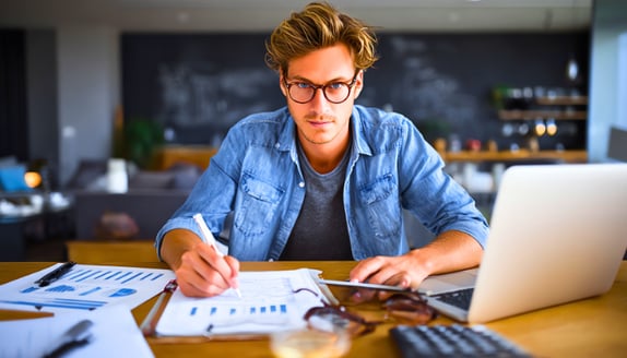 Business owner reviewing year-end financial reports with a calculator and laptop on the desk.