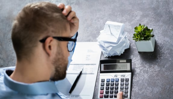 Small business owner reviewing invoices and calculating expenses while managing cash flow pressure.