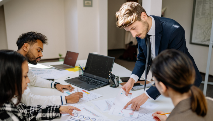 Small business team reviewing charts and reports in planning meeting to avoid common causes of business failure