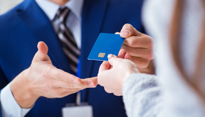 A small business owner receiving a business credit card, representing how business credit tools can support expenses but still require responsible use.