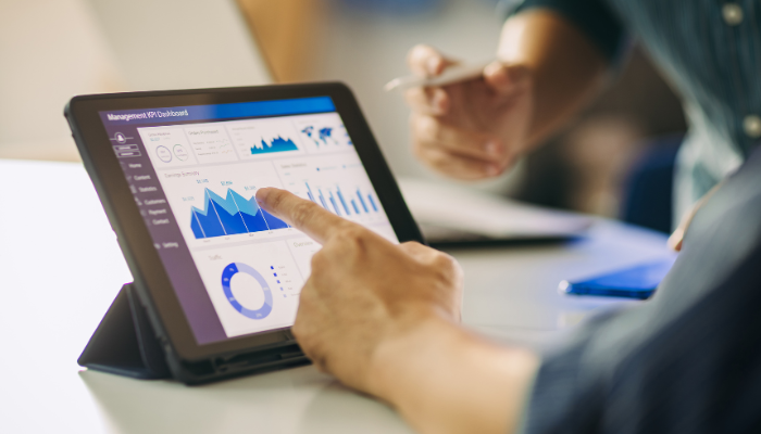 A business owner reviewing financial data on a tablet with a colleague, representing real-time cash flow decisions and short-term funding needs.
