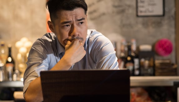 Business owner reviewing work and financial decisions on a laptop before taking on more client work