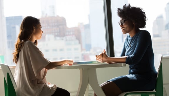 Two professionals in a calm one-on-one meeting representing a beneficiary experience that remains steady during factoring