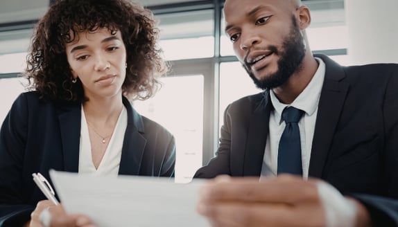 Two business professionals reviewing payment paperwork during a factoring-related discussion