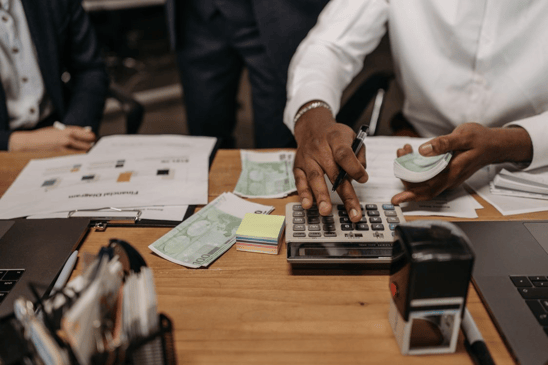 Business owner reviewing funding calculations and financial documents while assessing invoice factoring terms, growth restrictions, and working capital availability.