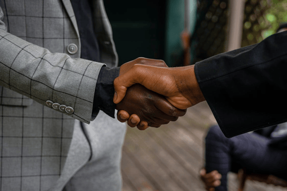 Close-up of two business professionals shaking hands, representing a partnership with a factoring company to improve cash flow and unlock working capital.