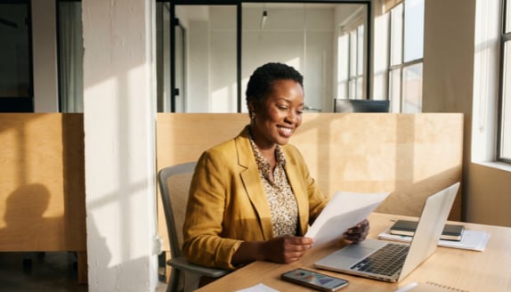 Businesswoman reviewing documents at her desk while staying organized as work increases