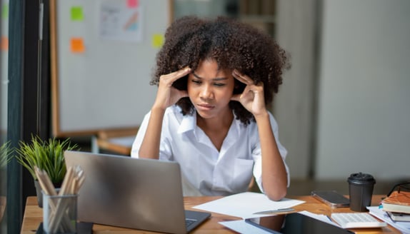 Professional woman looking stressed while working at a laptop despite strong business activity