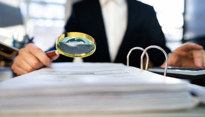 Individual in suit holding magnifying glass examining updated ERC guidelines